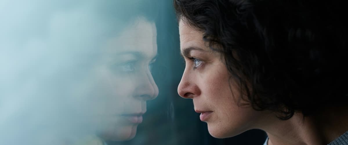 A woman sitting quietly, looking thoughtful and a little overwhelmed